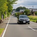 動物との衝突事故における警察への報告義務と保険適用外となる可能性を説明するため、自然光の住宅街の道路と野生動物の様子を表現した画像。