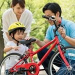 10月から自転車保険の加入義務化に向け、親子で自転車の安全点検を行っている場面。正しい乗り方を学ぶ大切さを伝える。