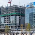 新潟駅直結のオフィスビルと商業施設を整備する万代口東地区開発の工事シーン。地域活性化に貢献する姿を捉えた現代的な風景。