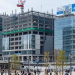 新潟駅直結のオフィスビルと商業施設を整備する万代口東地区開発の工事シーン。地域活性化に貢献する姿を捉えた現代的な風景。