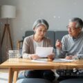 75歳以上の後期高齢者医療費を正しく理解する姿を描いたシーン。高齢者の夫婦が医療費に関する書類を話し合う様子を表現。