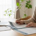 保険証が7月末で利用終了することの注意点を示す、現代日本の家庭で書類を整理しているシーン。医療費10割負担のリスクがテーマ。