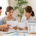 死亡保険金2000万円の受取時に判明した保険会社の支払漏れについて、家族が書類を確認する様子を描写。