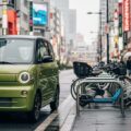 ミニカー登録したジャイロの任意保険とファミリーバイク特約の適用範囲を解説するためのシーン。現代日本の都市風景の中に、独特なデザインのミニカーが駐車している様子。