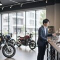 自民党二輪車問題対策PTが提言したバイク店の自賠責保険取り扱い維持の様子。地域密着の交通安全拠点としての重要性が強調される場面を描写。
