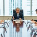 マイナンバーカード義務化を見送り、政府が示した理解促進と利便性向上の戦略についての議論が行われている現代日本のオフィスシーン。