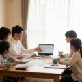 個人年金保険の課税の仕組みと年金形式または一括受け取りの違いについて、家族が話し合う現代日本の室内の様子を表現。