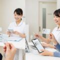 健康保険証による資格確認が7月末で終了しマイナ保険証と資格確認書へ移行する様子を示した日常の医療シーン。
